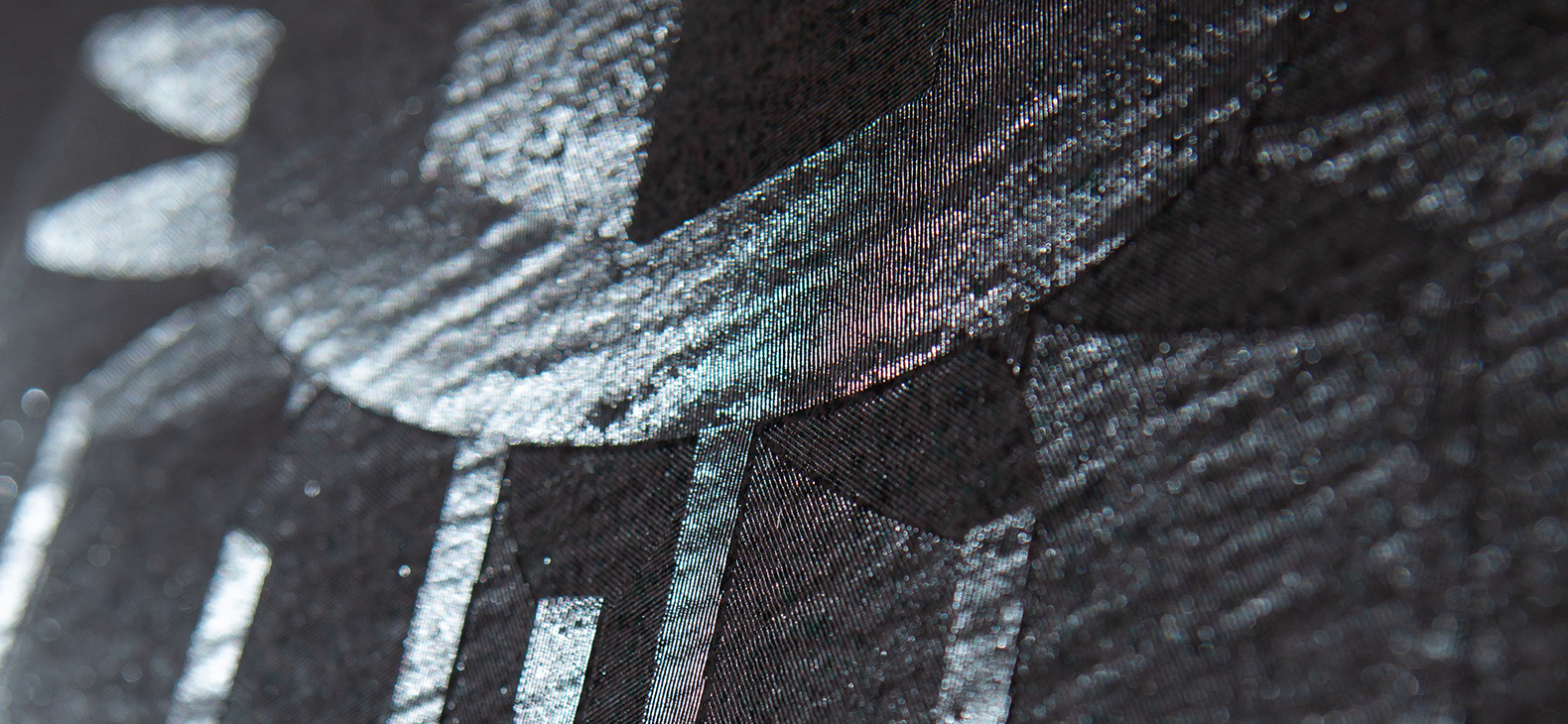 Detail from photograph of one of the works of the Hungarian artist Ádám Varga. You can see a detail shot of a black canvas into which patterns were deliberately milled. Under light irradiation a motive comes to light. Work 04-17 from the series "Engraved Canvases".