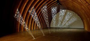 Bild vergrößern: Total view of the installation by artist Zipora Rafaelov in the barrel vault of the Schafhof - European center for art of the district of Upper Bavaria. Delicate, fan-shaped installation made of 3D filament in wooden barrel vault. White motifs on seven panels stretched from the floor to the vault of the ceiling. Artist: Zipora Rafaelov; Photo: Klaus Lipa