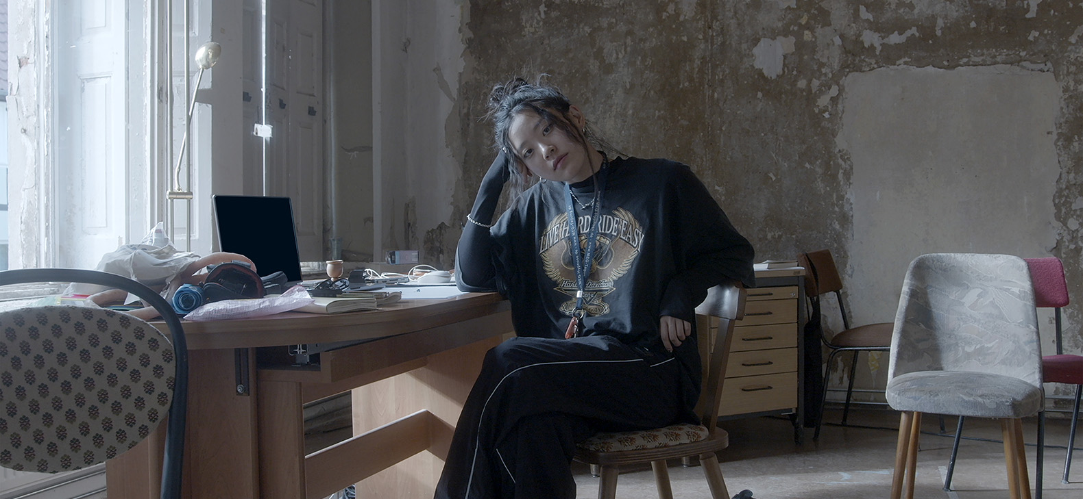 Artist-in-Residence: Eunju Hong, Fokus > Kosice, Aufenthalt in Kosice im Herbst 2023: Bild: Portrait der Künstlerin an einem Schreibtisch sitzend